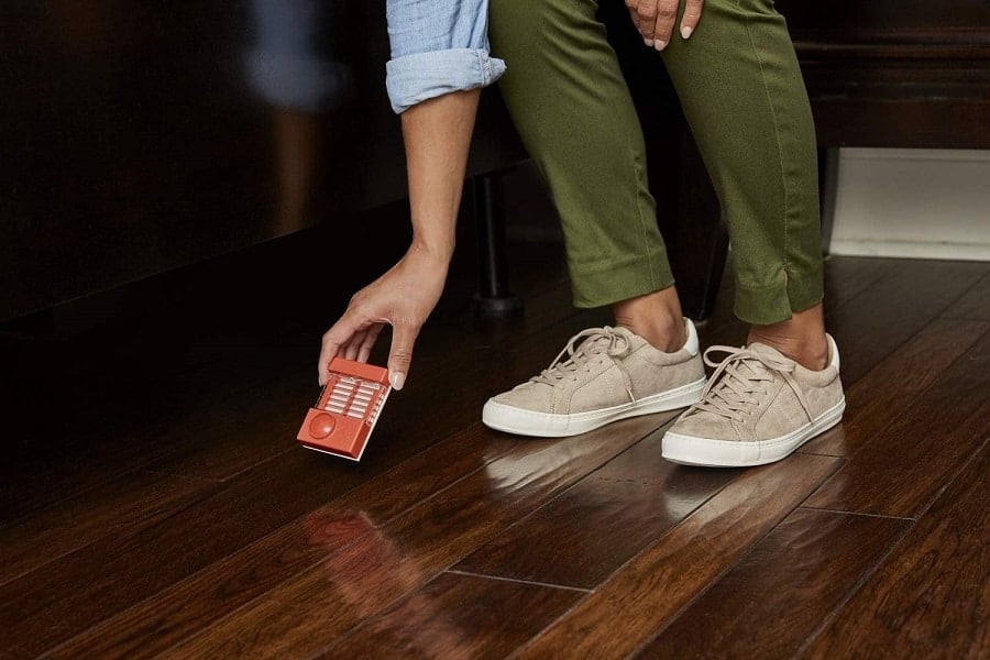 person setting a bed bug trap under the bed