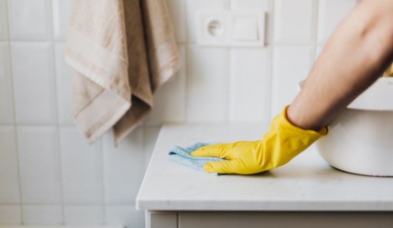 gloved hand wipes the table