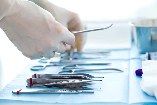 person in a rubber gloves holding medical instruments